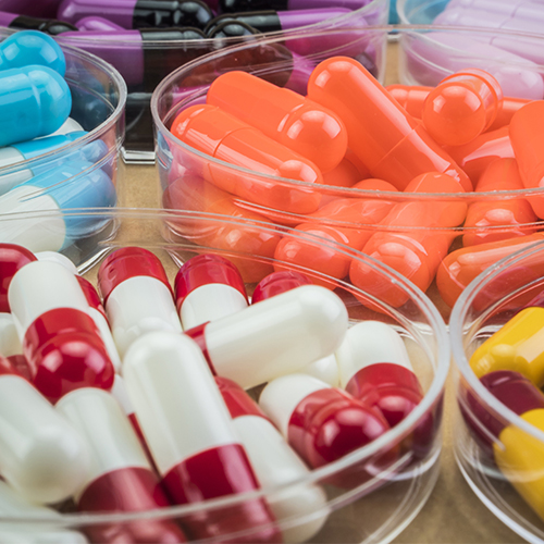 Close up picture of transparent bowls holding different colour pills