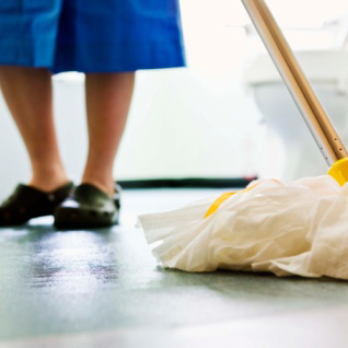 Picture shows someone's legs and their blue dress and black shoes in the background with a white mop in the front