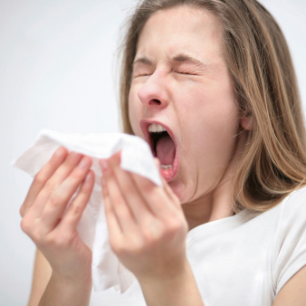 Woman sneezing and holding a white tissue