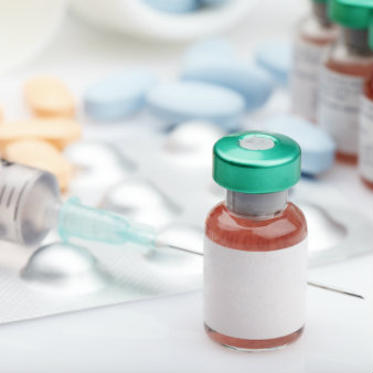 Medication bottle with syringe, bottles and pills in the background